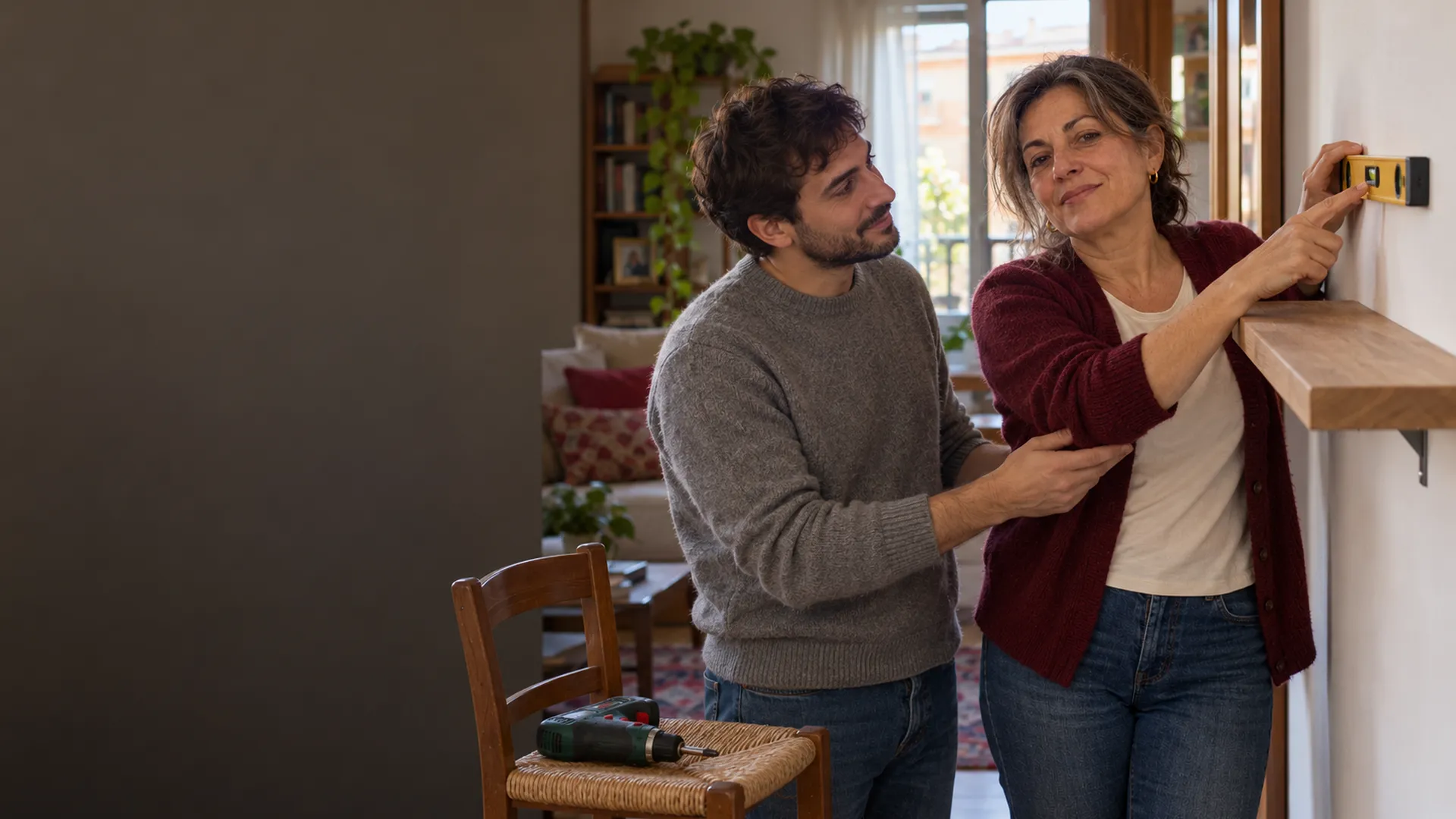 Patrizia insegna al figlio ad appendere una mensola con la livella in mano